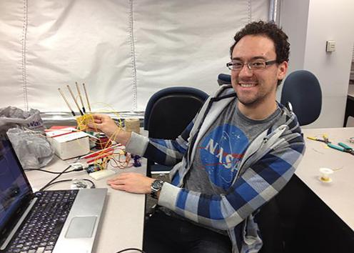SEDS Student at a desk in a NASA shirt